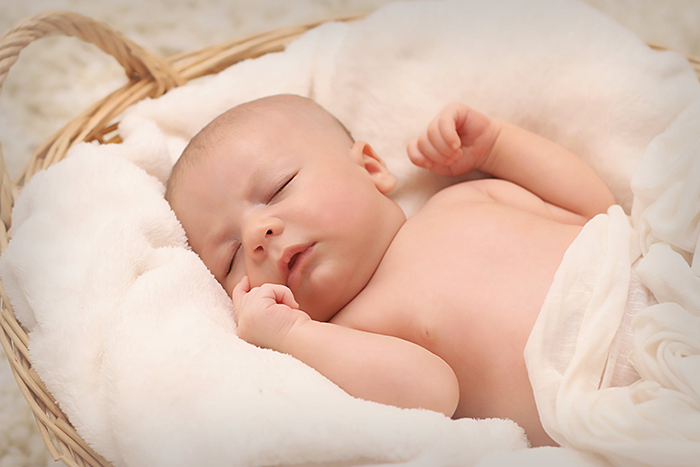 A peaceful baby, swaddled in a soft blanket, sleeps soundly on their back, a safe and recommended sleep position for infants.