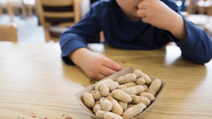 A curious child reaches for a bowl of peanuts, unaware of the potential allergy risks.