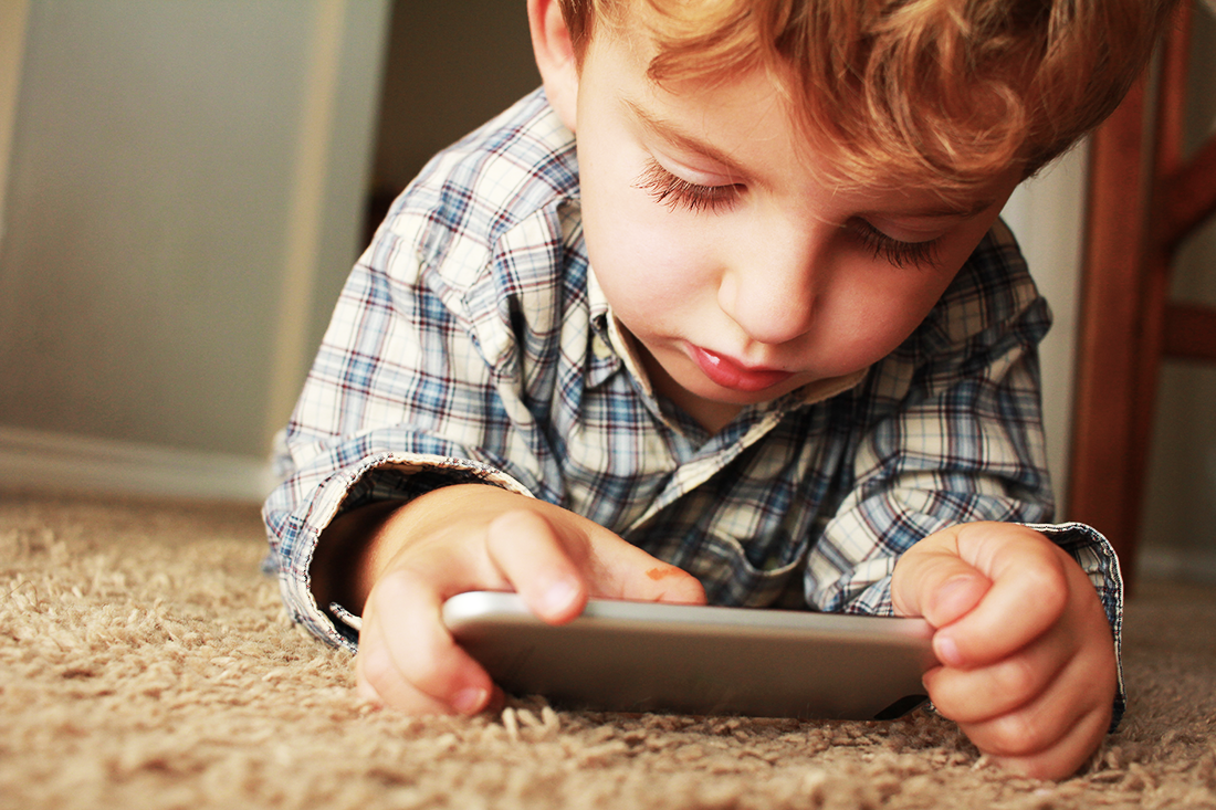 A curious child, navigating the digital world, interacts with a smartphone, exploring apps and games.