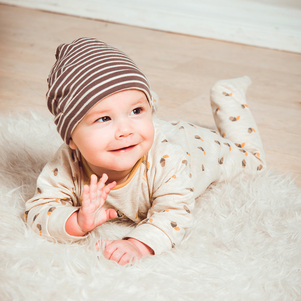 A curious baby, lying on their tummy, waves their arms and legs, exploring their surroundings and practicing their motor skills.