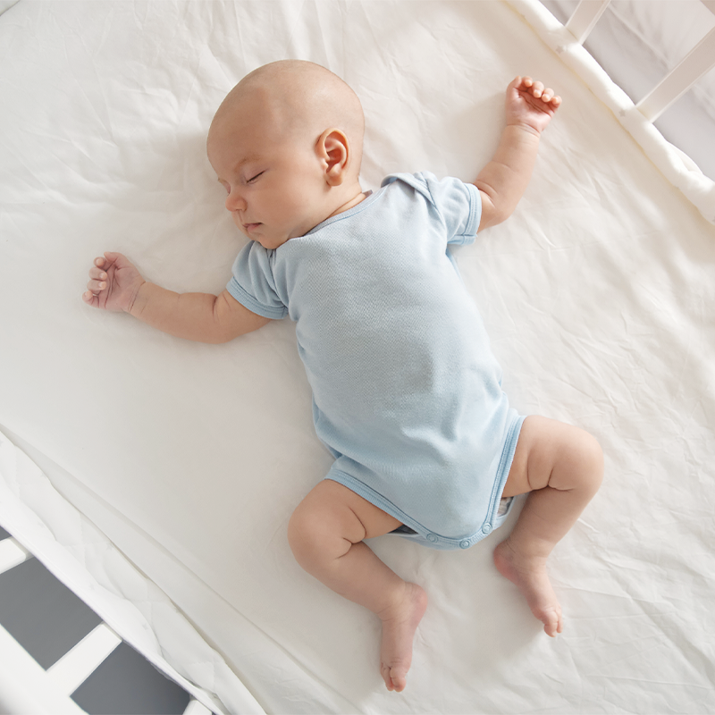 A peaceful newborn baby, lies on their back with arms outstretched, a serene image of infancy.