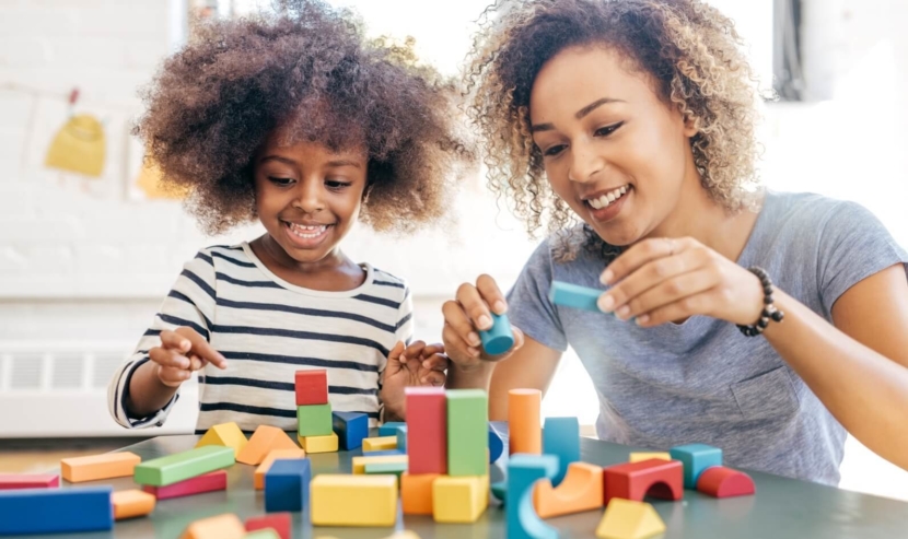 A loving mother and her child engage in a fun and educational activity, building towers with colorful blocks