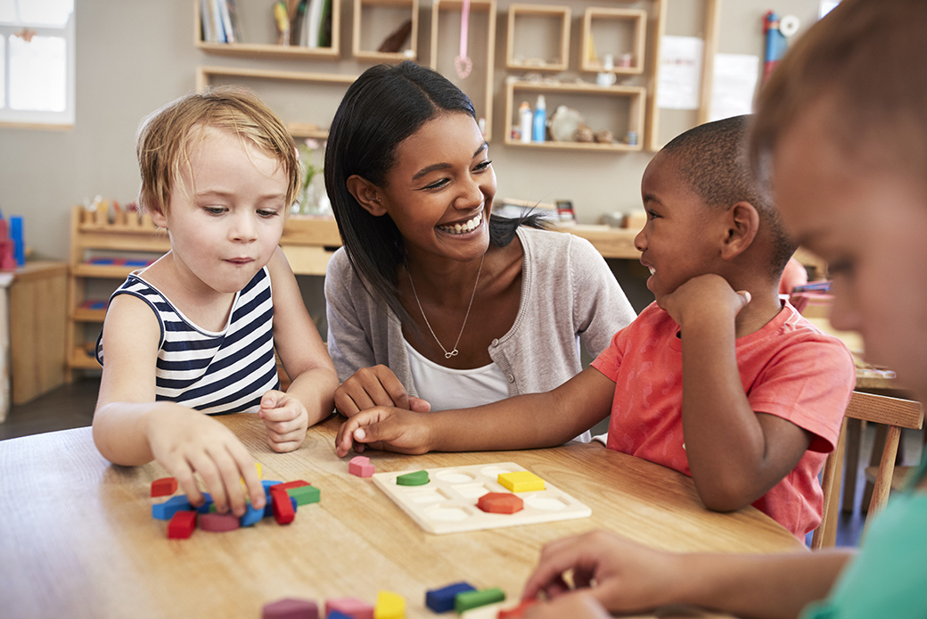 A group of enthusiastic young learners, guided by their Montessori teacher, engage in a hands-on activity using wooden shape.