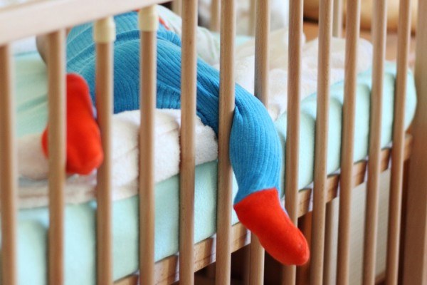 A curious toddler's foot dangles over the edge of the crib.