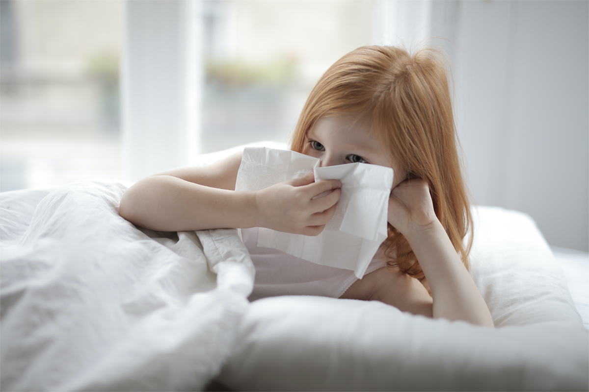 Little girl on bed while holding a Kleenex