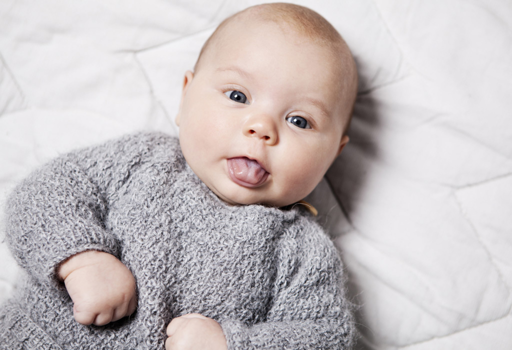 Baby laying down while sticking their tongue out