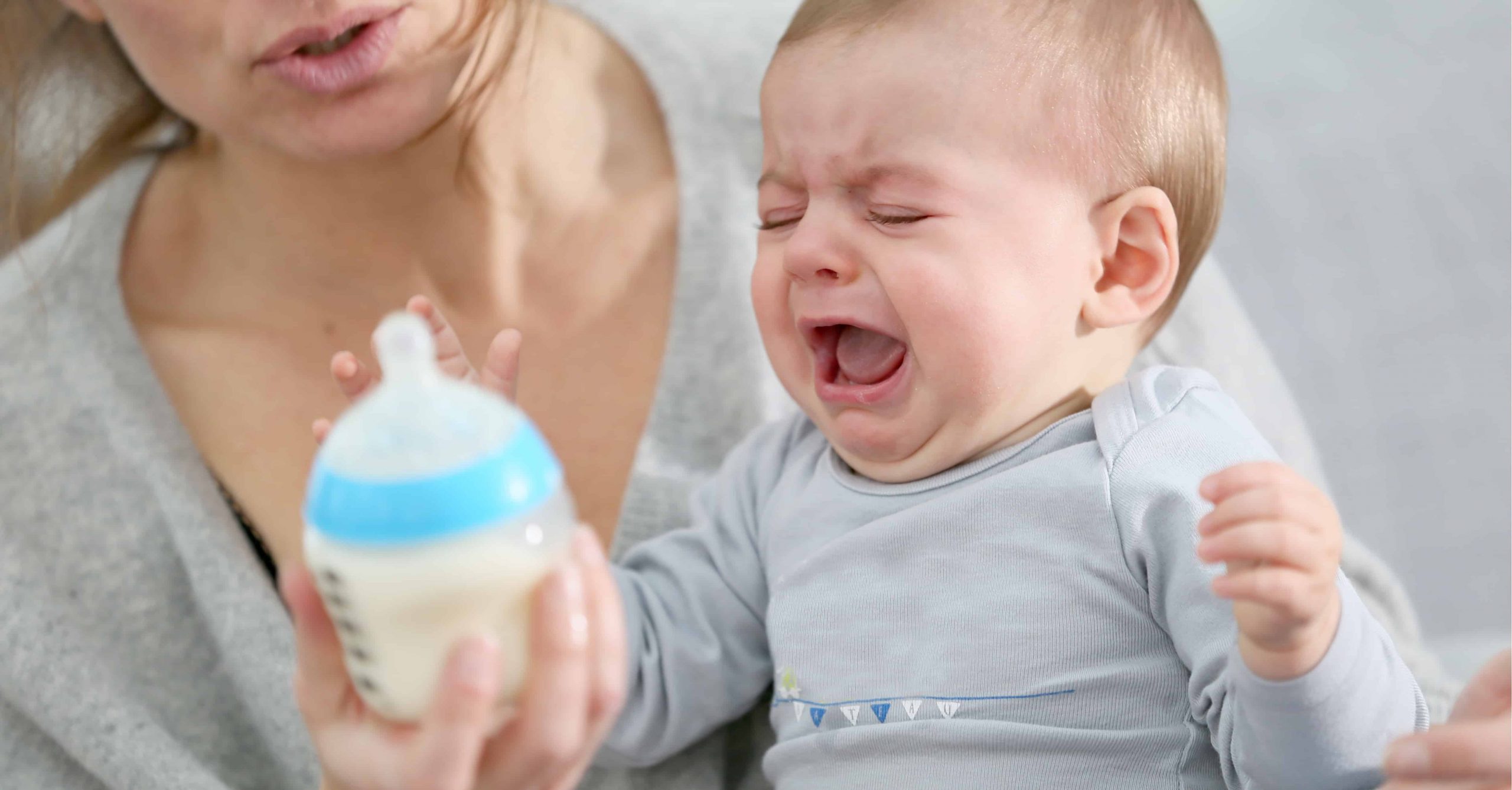 Baby crying while reaching for bottle