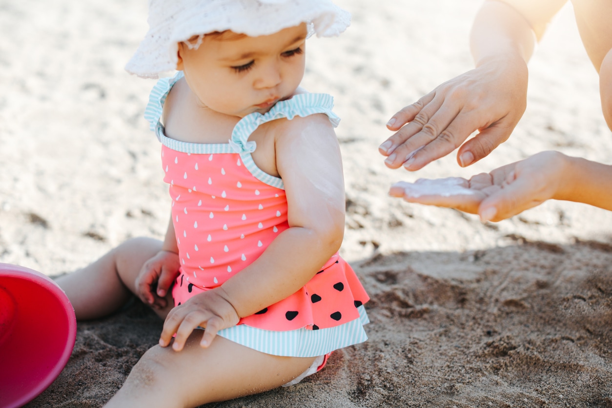 Person putting sunscreen on baby girl