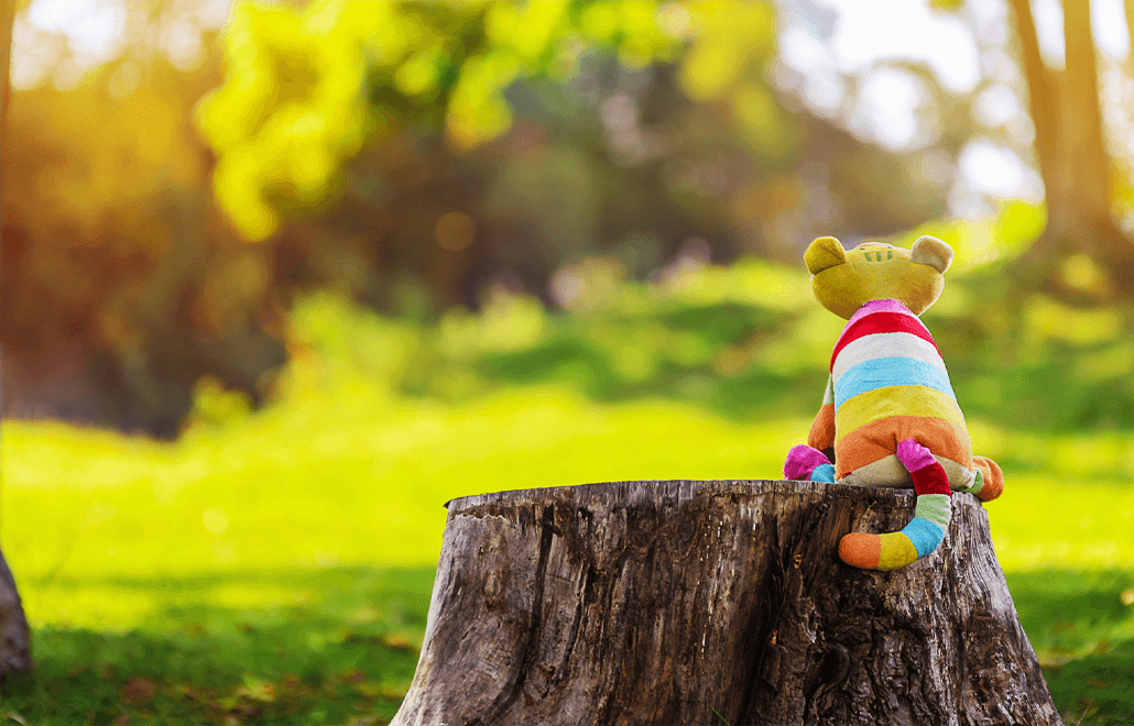 A stuffed animal, sitting on a tree, symbolizes the child's imaginary friend, a companion in their imaginative world of play.