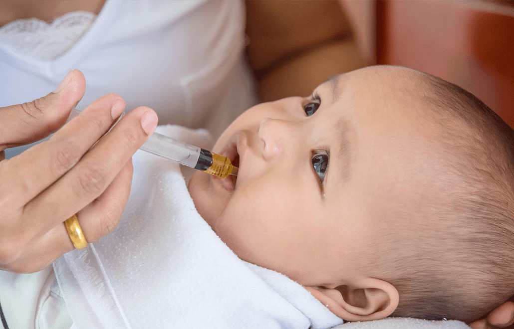 A caring mother administers medicine to her child, ensuring they feel better soon.