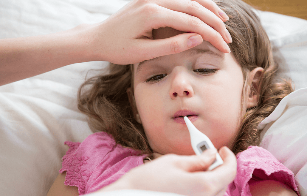 A concerned parent uses a thermometer to check their child's temperature, assessing their health during an illness.