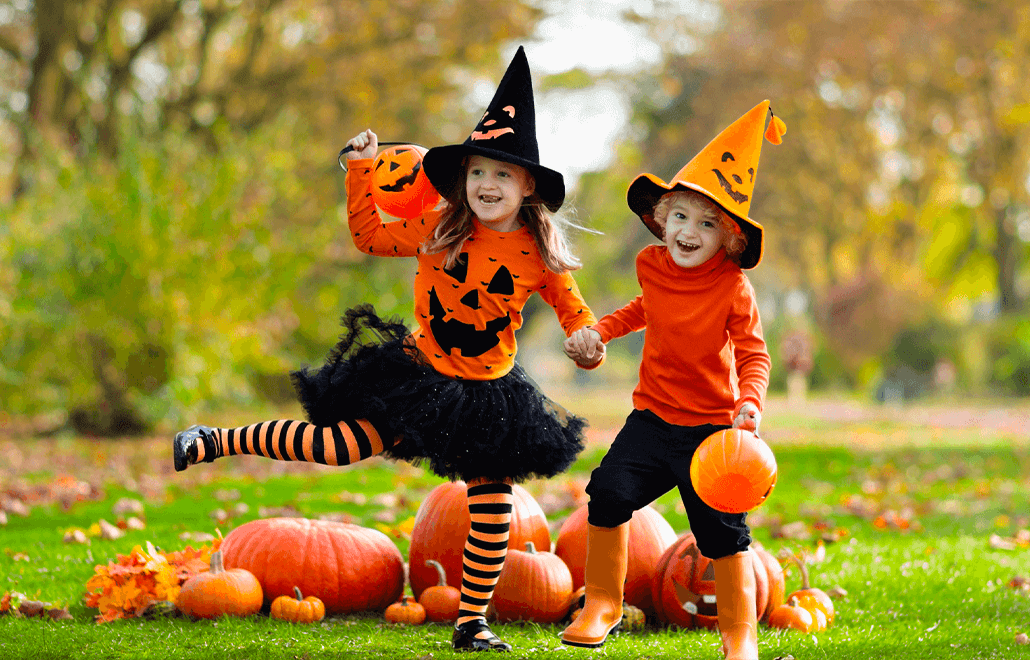 Two excited children, dressed in adorable Halloween costumes, hold hands while trick-or-treating, sharing the joy of the spooky season.