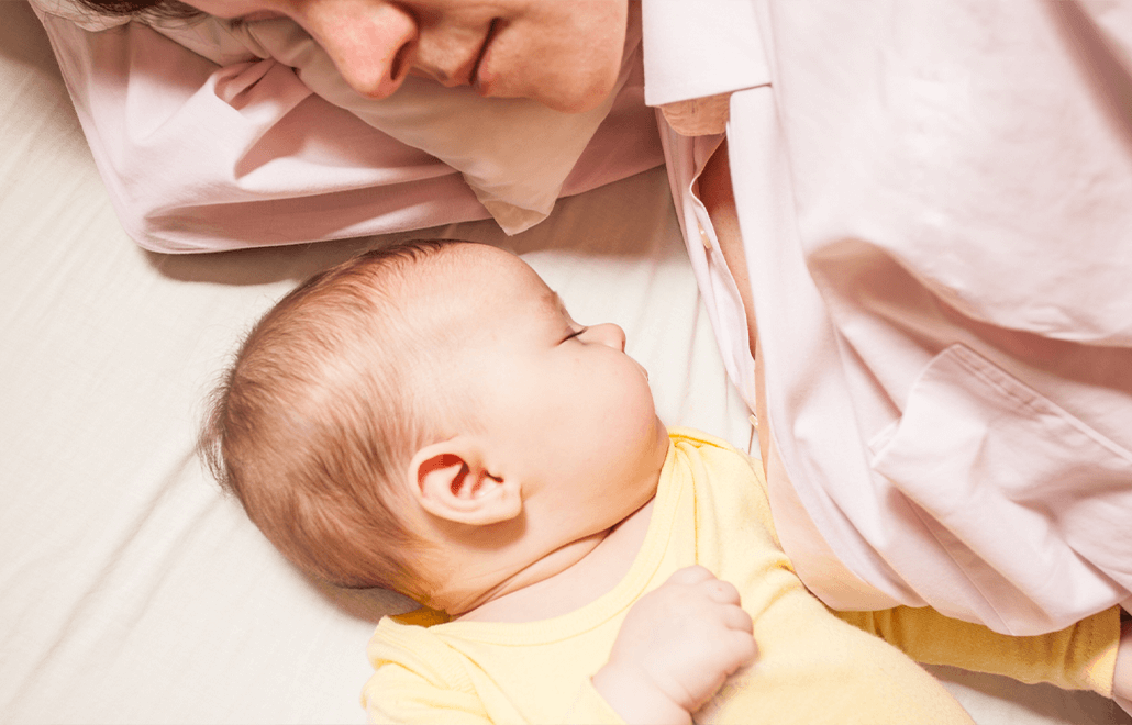 A mother and her newborn baby share a peaceful sleep, nestled together in bed.