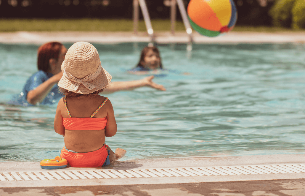 A happy child splashes and plays in a refreshing pool on a sunny summer day.