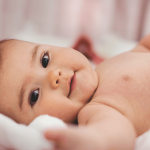 Smiling infant lying comfortably in bed