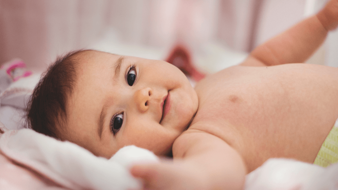 Smiling infant lying comfortably in bed