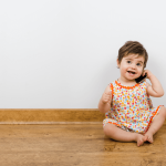 Happy baby sitting on the floor and talking on the phone