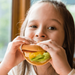 Child eating a healthy sandwich, promoting balanced eating habits