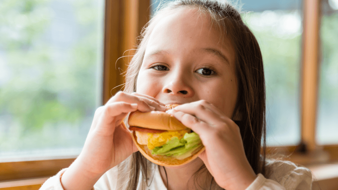 Child eating a healthy sandwich, promoting balanced eating habits