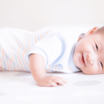 Happy newborn during tummy time for muscle and sensory development