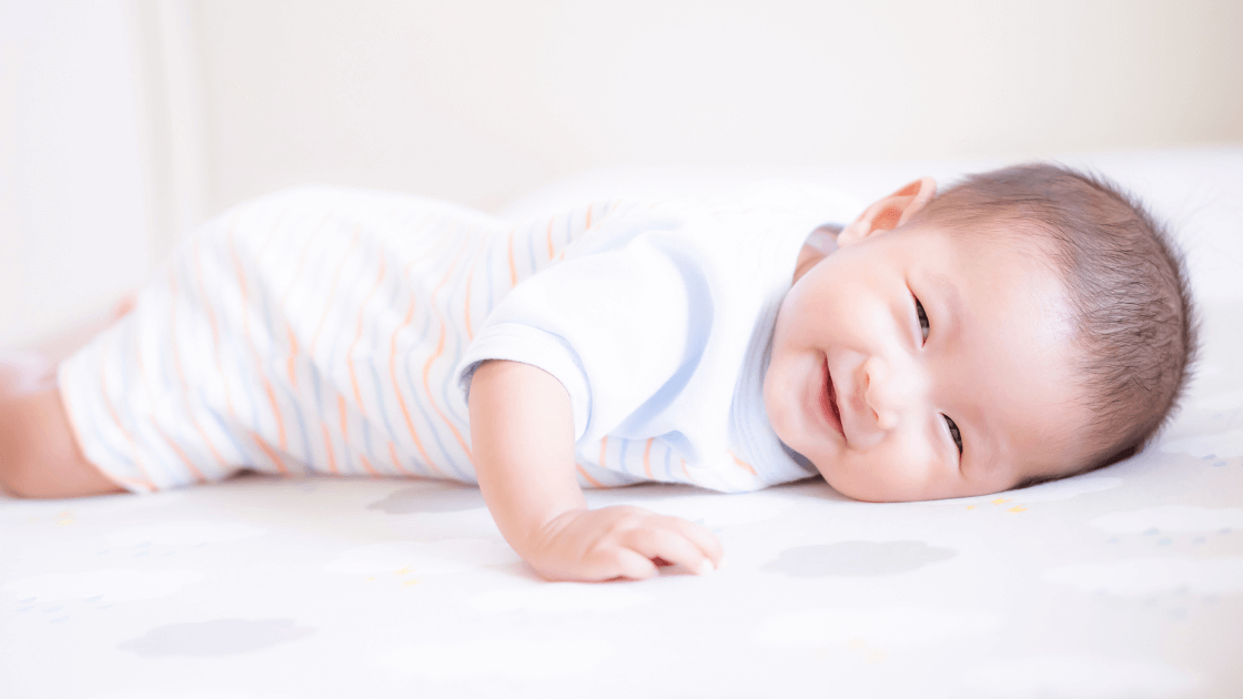 Happy newborn during tummy time for muscle and sensory development