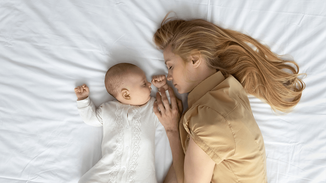 A parent falling asleep while trying to help her baby that is fighting sleep