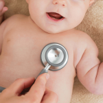 A pediatrician listing a child’s heart during a routine check-up.