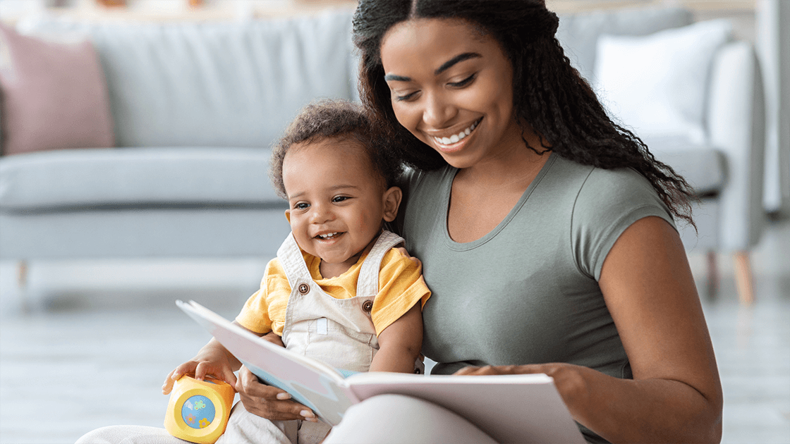 Parent reading a storybook to a smiling baby