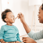 A toddler eating a healthy protein-rich meal, including eggs, yogurt, and lean meats.