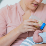 A newborn baby breastfeeding, representing cluster feeding and early infant feeding patterns.