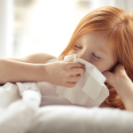 Child inside with a tissue, showing signs of spring allergies