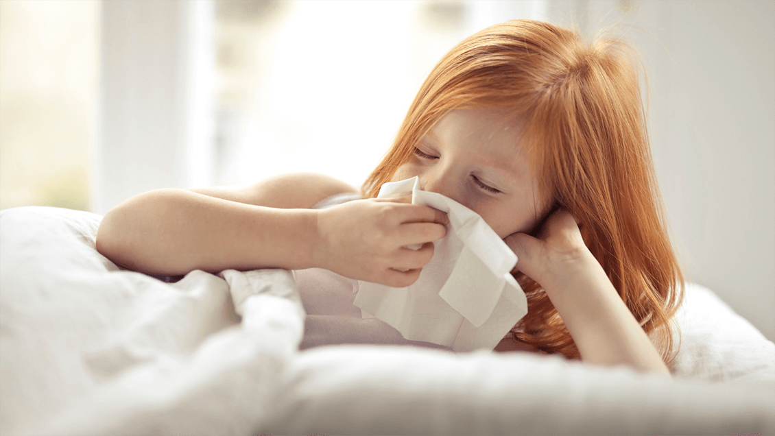 Child inside with a tissue, showing signs of spring allergies