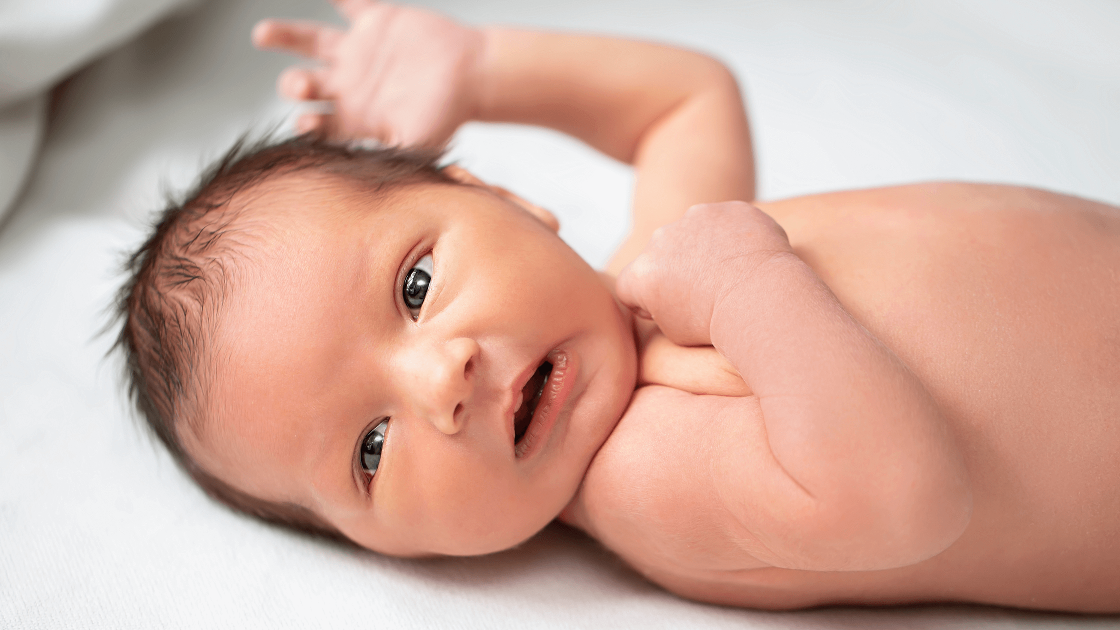 Close-up of a newborn baby with open eyes looking upwards, relevant to understanding baby eyesight.